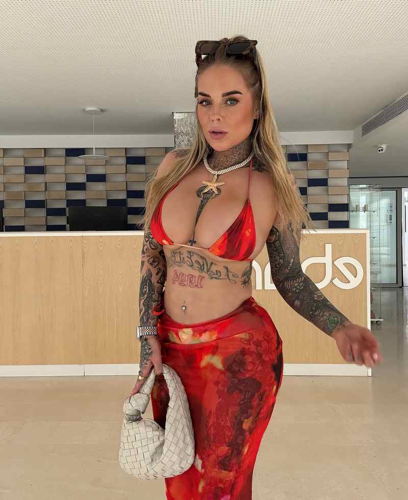 Gia Clarke hat ein feuerrotes Outfit an und zeigt viel von ihren Brüsten