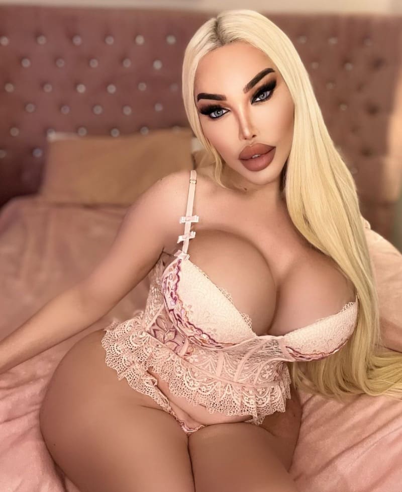 Jessica in pink outfit with massive tits on bed