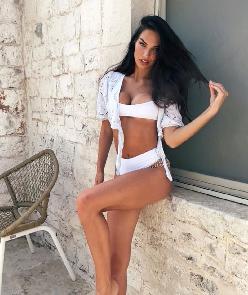 Daria in white bikini next to wall