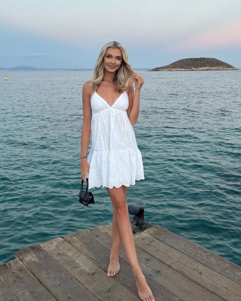 Krystina in white dress next to water