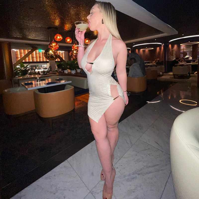 Liana Wilder hat ein Cocktail-Kleid an und leckt am Glas