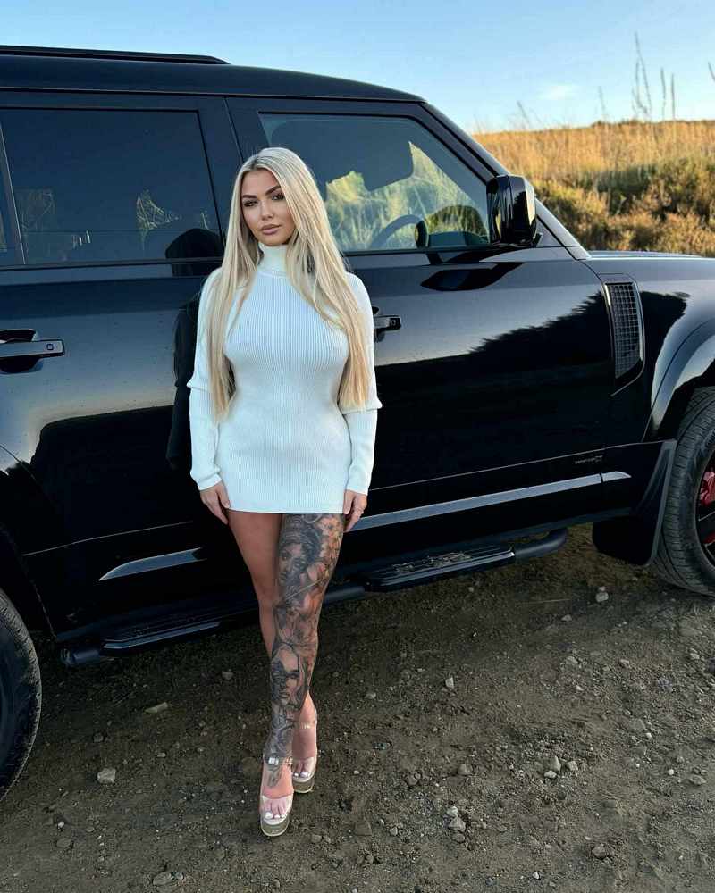 Morgan Holly Moore in einem edlen Nippel-Outfit vor einer Luxuskarre