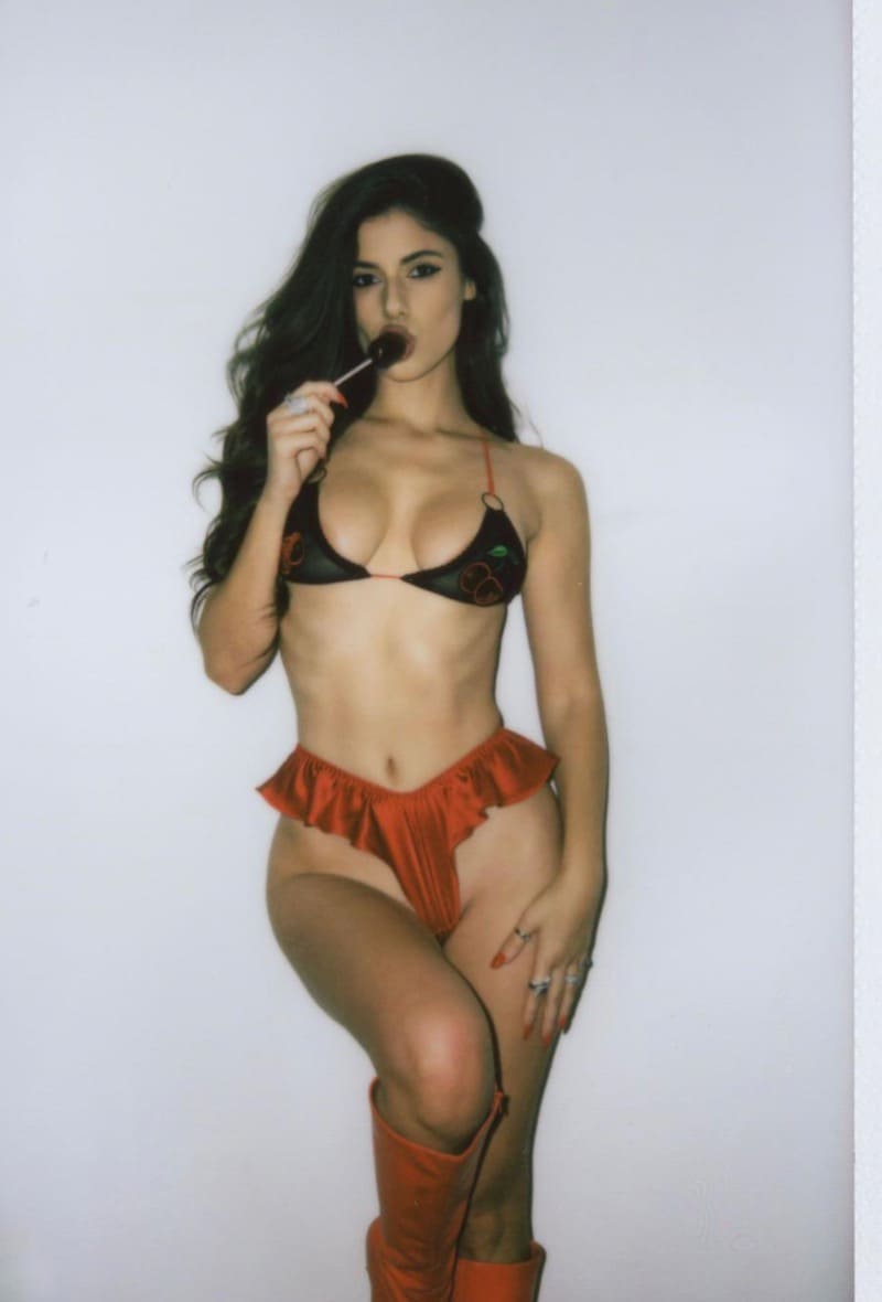 Ines sucks on lollypop while posing in lingerie