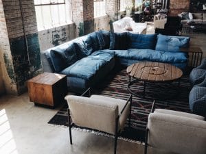 zitplek, blauwe bank, onafgewerkte mumren, ronde houten tafeltje, witte zitstoelen