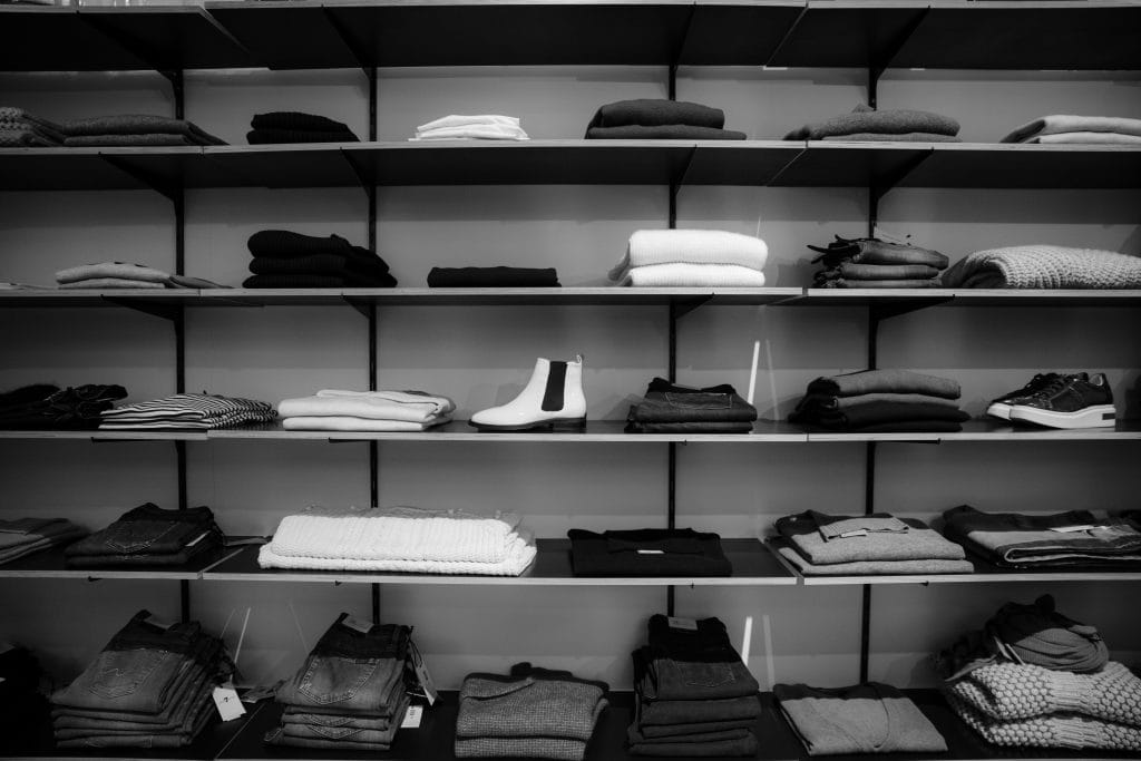 zwart-wit foto van kledingkast met kleine stapels mannenkleding