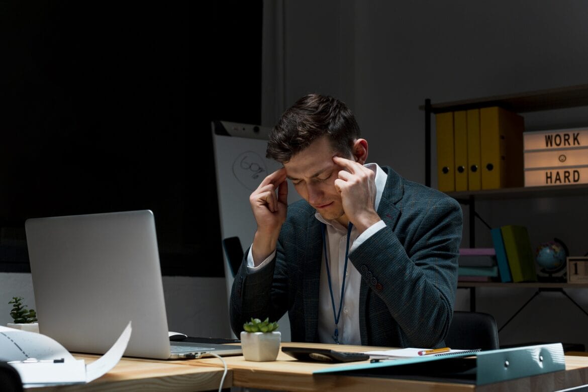 Man zit voor computer en werkt aan hustle cultuur