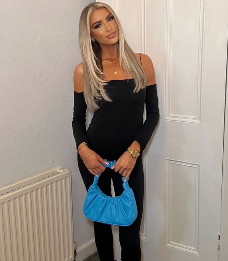Babe in strakke outfit met blauwe handtas