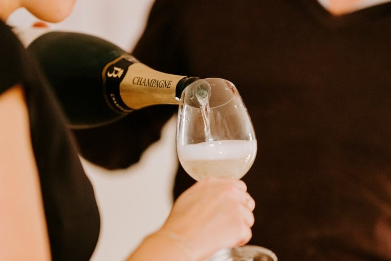 Persoon vult glas champagne