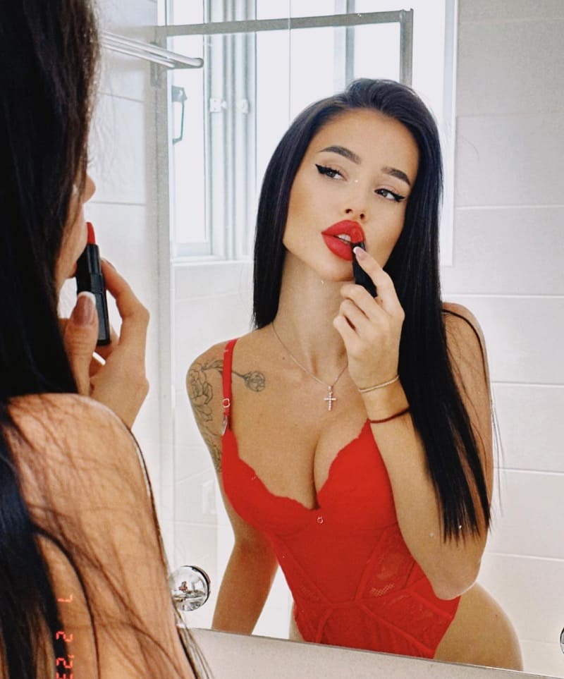 Babe in rode lingerie maakt lippen rood