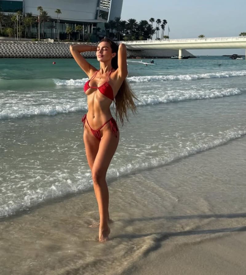 Sexy brunette in rode bikini op strand