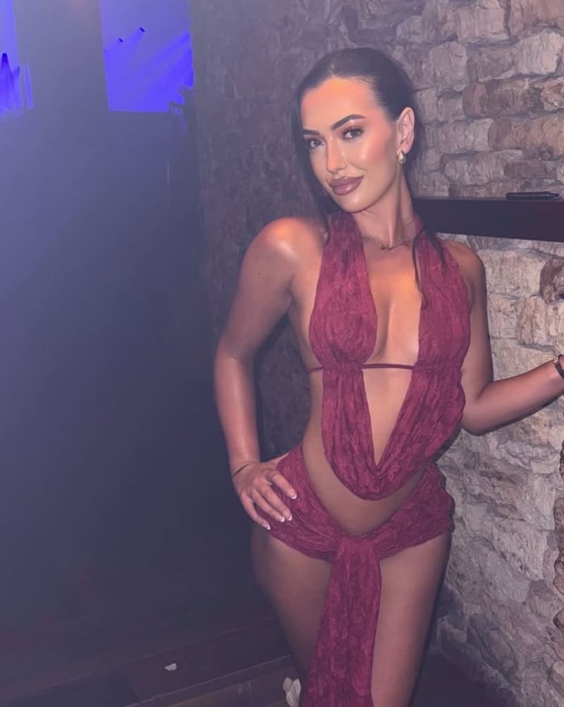 Annalise in sey rode jurk voor muur