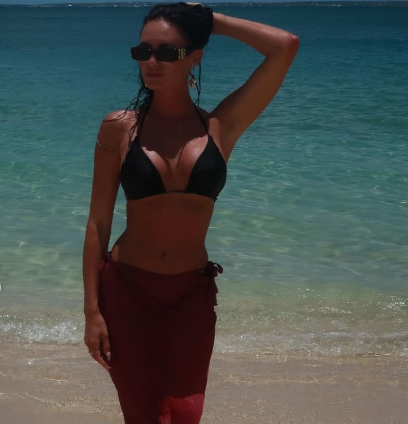 Brunette in black bikini on beach with nice blue water