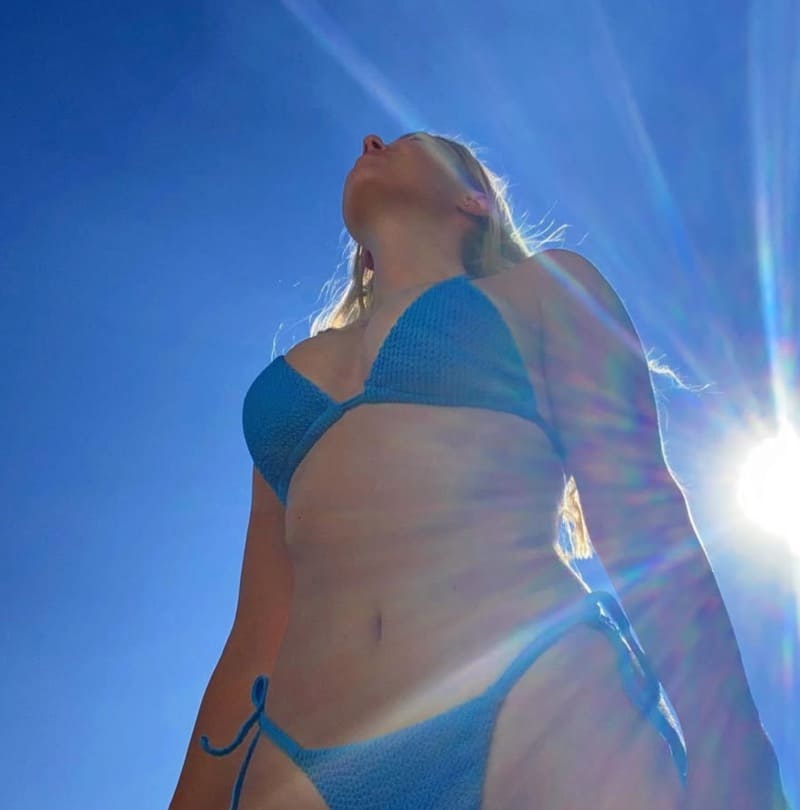 Claudia in blauwe bikini met zon in achtergrond