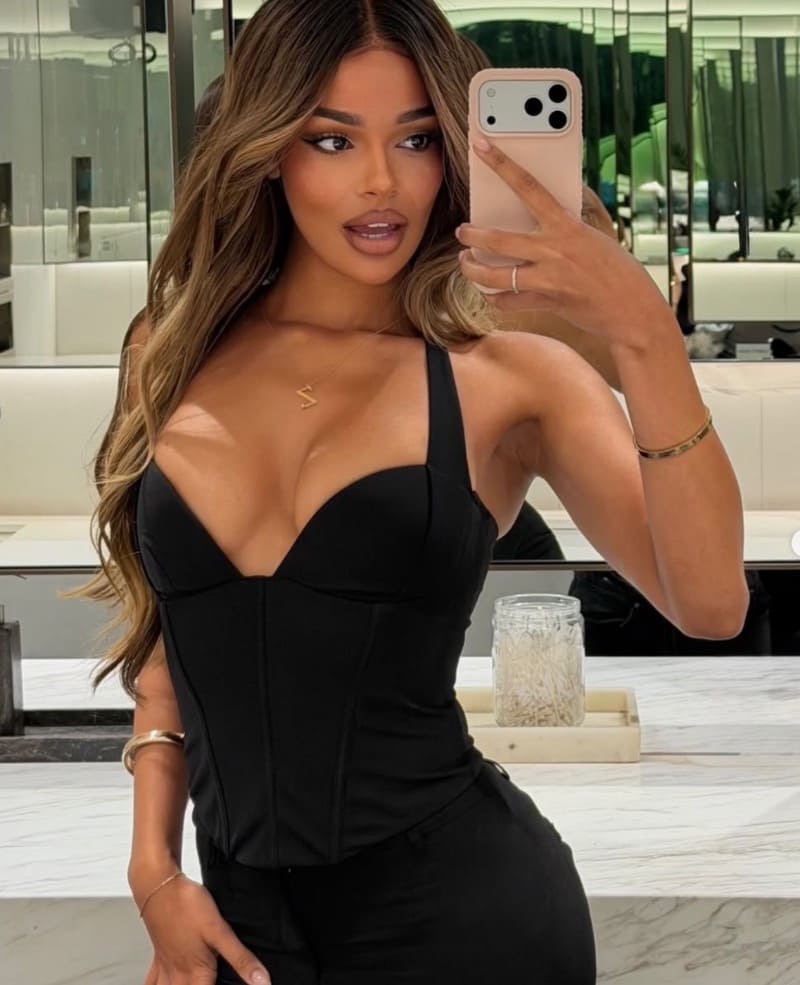 Zaria in strakke zwarte jurk met diepe decolleté