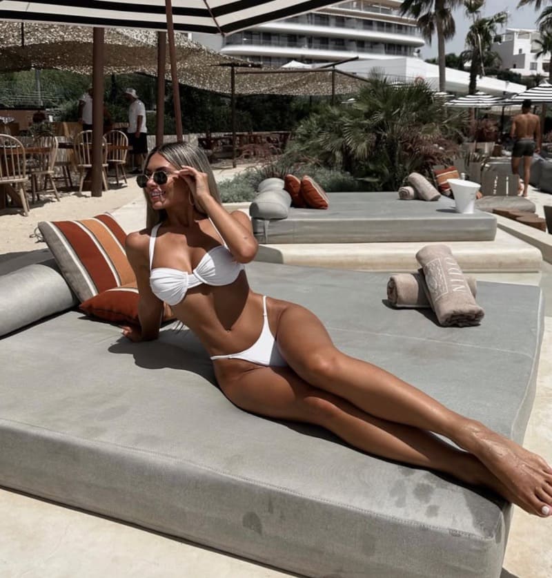 Sexy blondine in mini bikini op lounge stoel